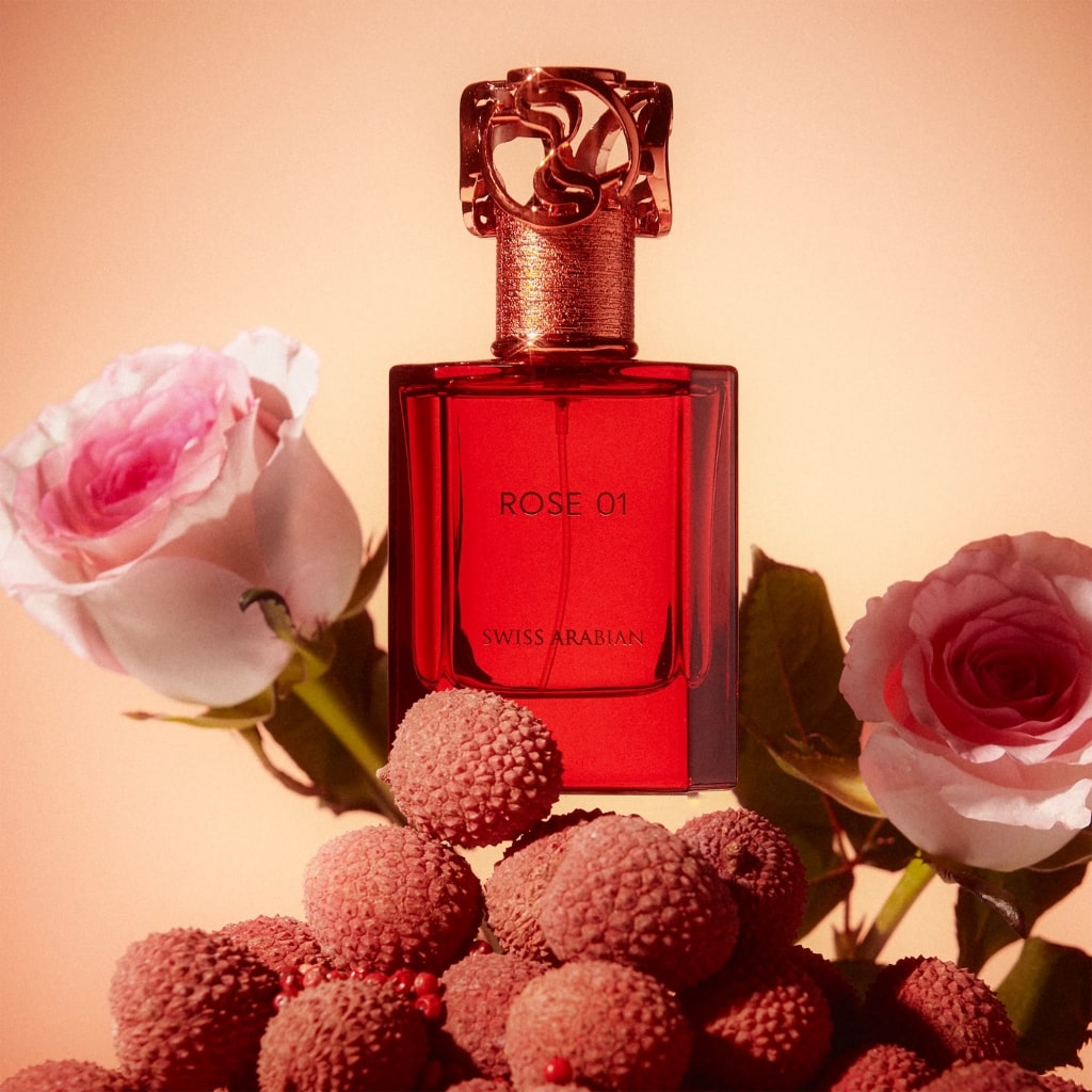 Damparfym Swiss Arabian Rose 01 i elegant röd flaska omgiven av rosor och lychee-frukt