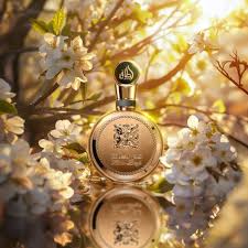 Lattafa Fakhar Gold unisex parfymflaska omgiven av blommor och soligt ljus